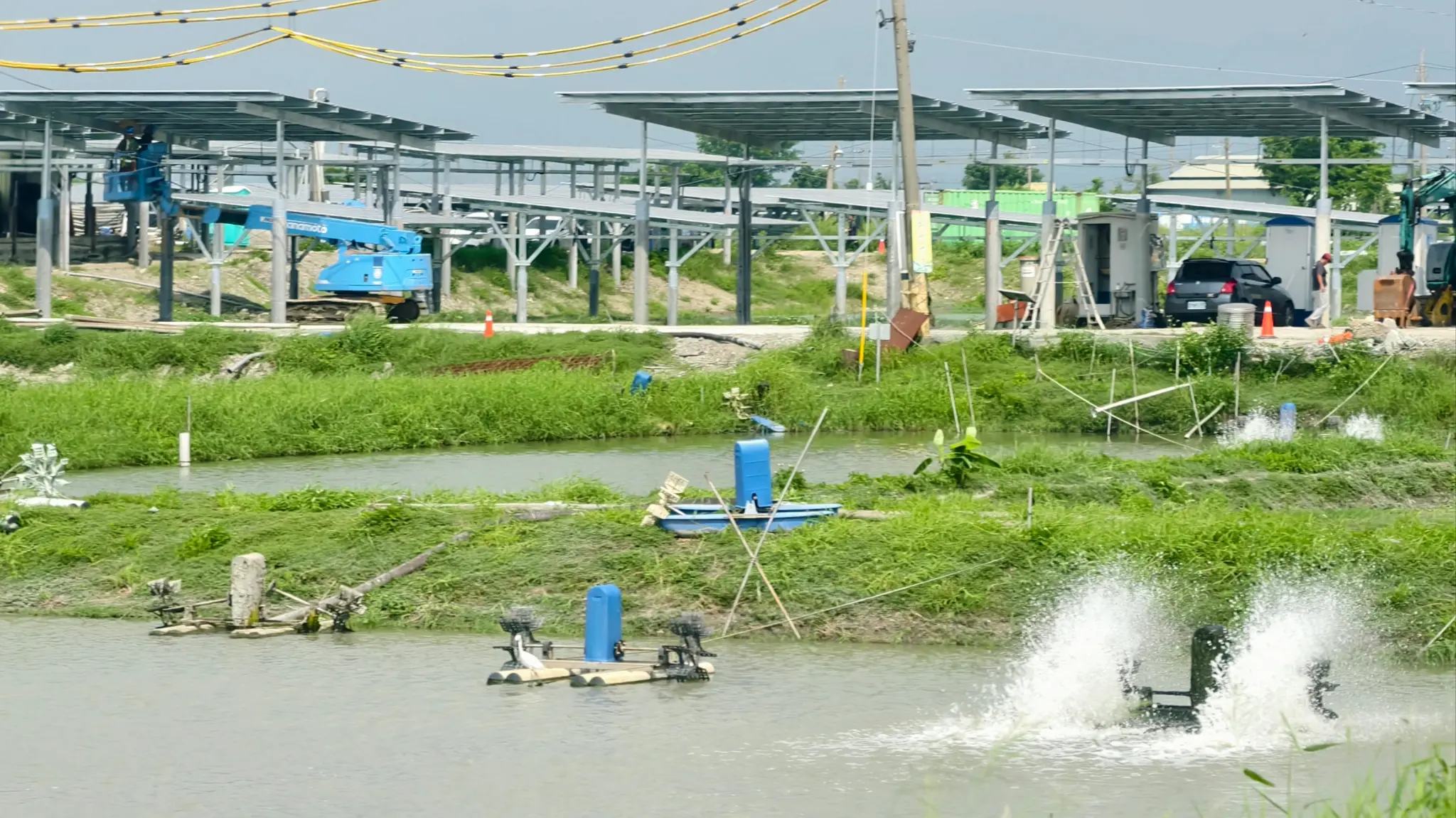 台南漁電共生案場現場,魚塭水車持續運轉,光電設施正在施作。