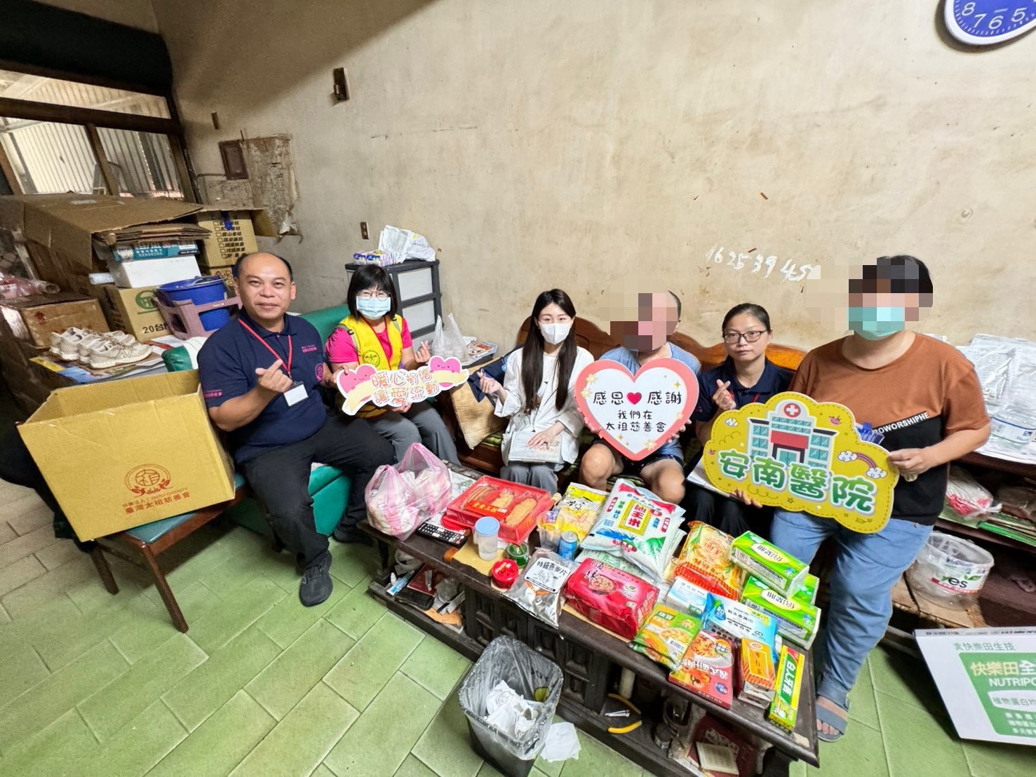 家庭關懷訪視合影,桌上可見白米與食品等物資,部分臉部已有馬賽克遮蔽
