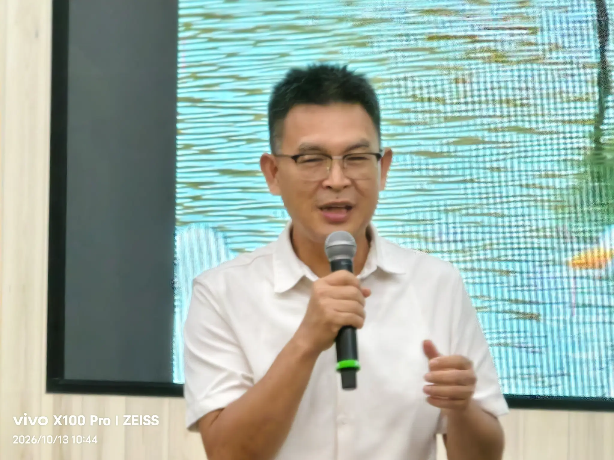 雲嘉南濱海國家風景區管理處代理處長莊名豪穿著白色上衣,於黑面琵鷺保育季行前記者會持麥克風發言。